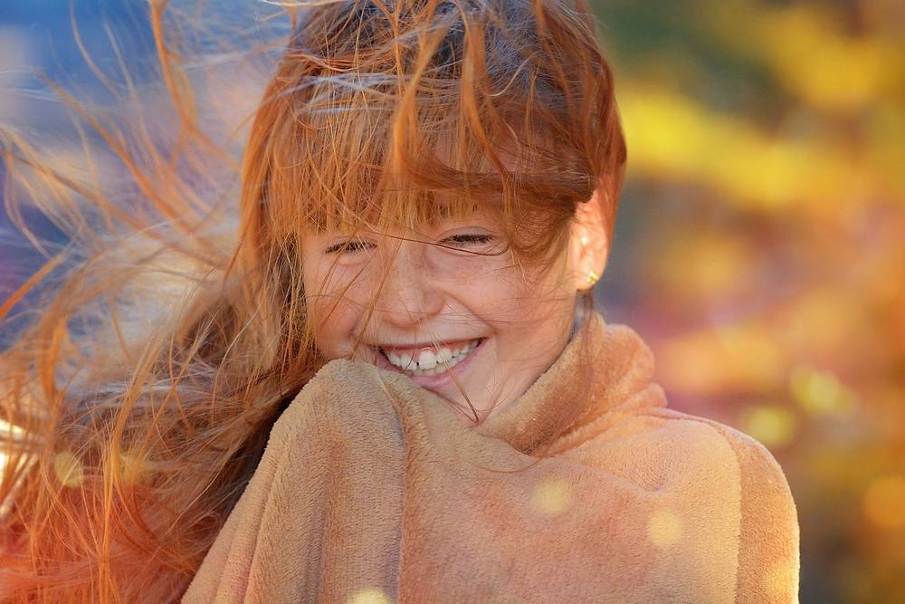 Lachendes Kind mit roten Haaren im Gegenlicht